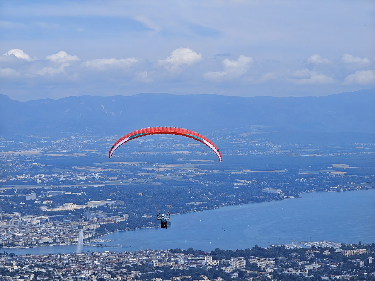Parapente rouge au-dessus d'un grand lac alpin